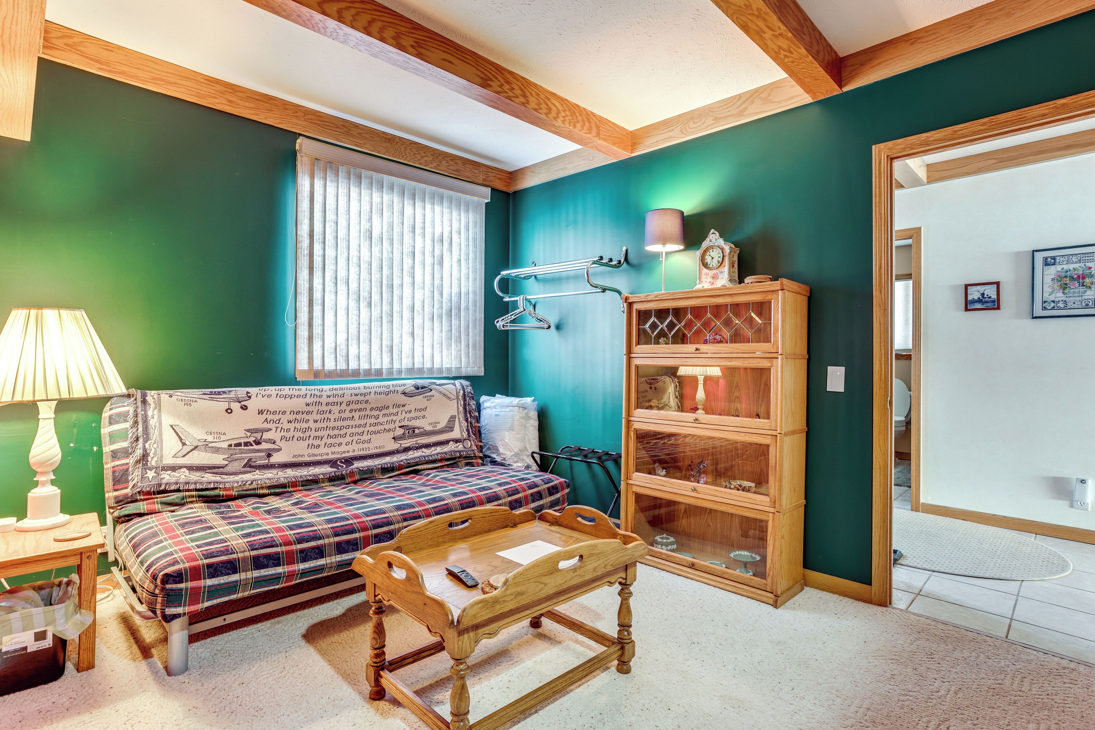 A cozy room with a plaid sofa, a wooden coffee table, and a wooden cabinet with glass doors.