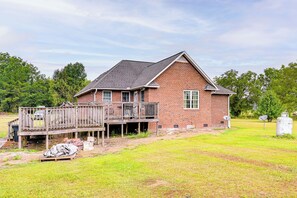 Une maison de plain-pied en briques, dotée d’une terrasse en bois et d’une antenne parabolique.