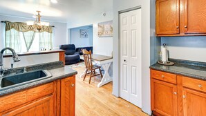 A kitchen with wooden cabinets, a sink, and a dining area with a table and chairs. - Peaceful Getaway in Blonts Creek Near Washington (Blounts Creek)
