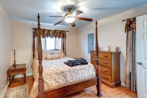 Un lit à baldaquin avec un ventilateur de plafond, une commode en bois et une table de chevet avec une lampe.