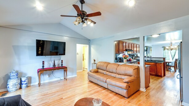 A spacious living room with a brown leather sofa, a flat-screen TV mounted on the wall, and a ceiling fan. - Peaceful Getaway in Blonts Creek Near Washington (Blounts Creek)