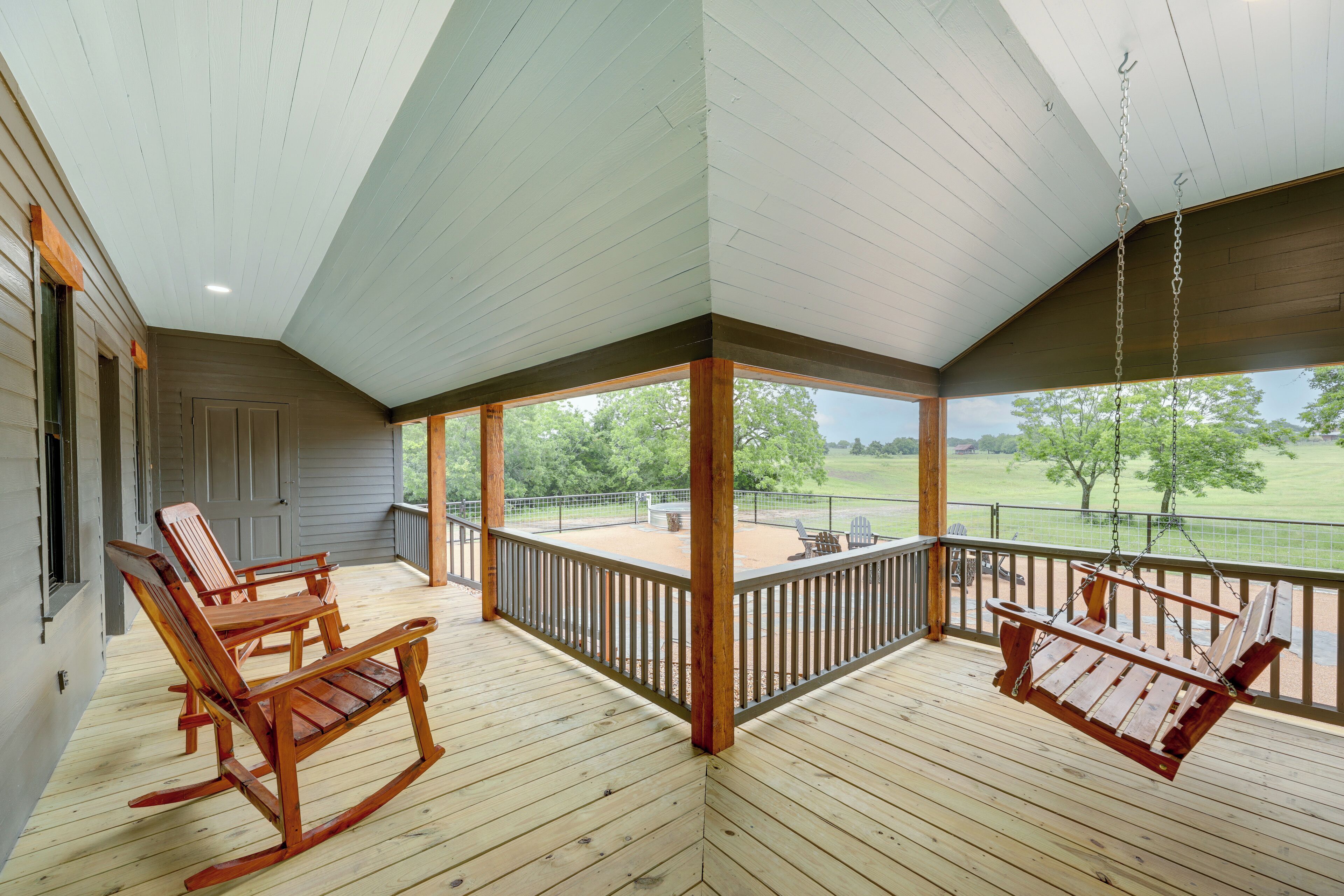 Eine überdachte Veranda mit Holzschaukelstühlen und einer Hängematte, mit Blick auf eine Rasenfläche.