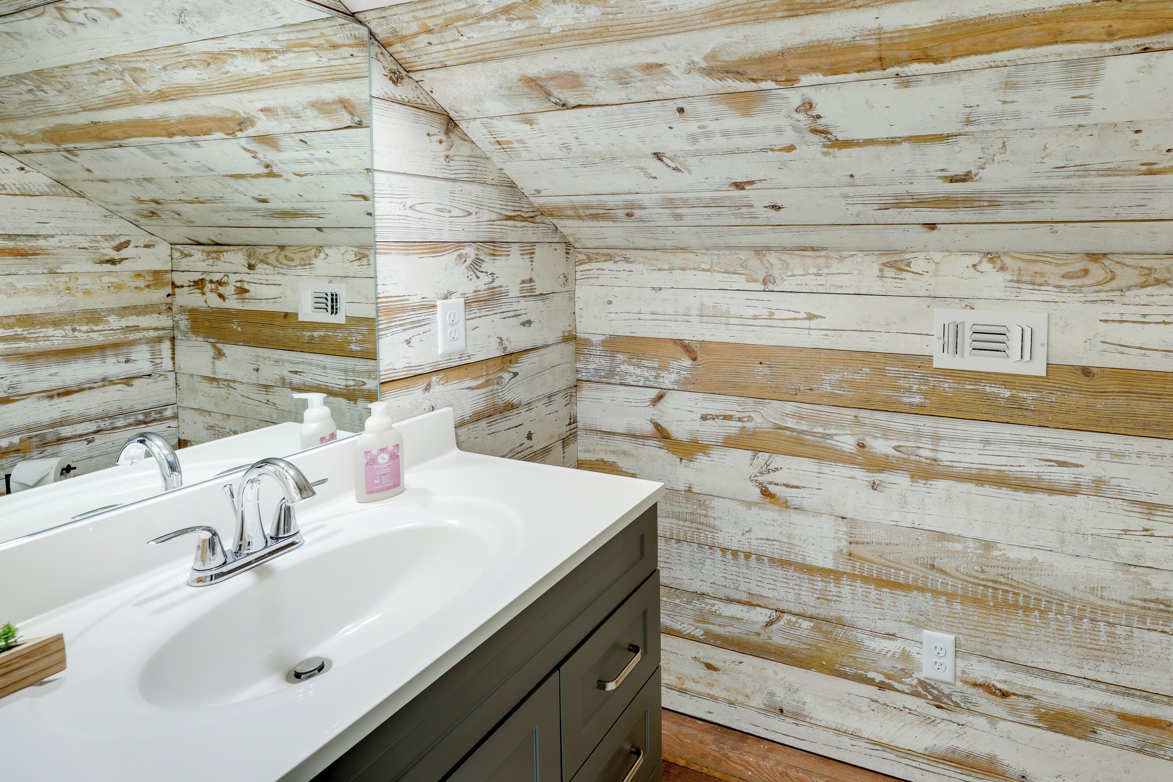A bathroom with a white sink, chrome faucet, and wooden wall paneling.