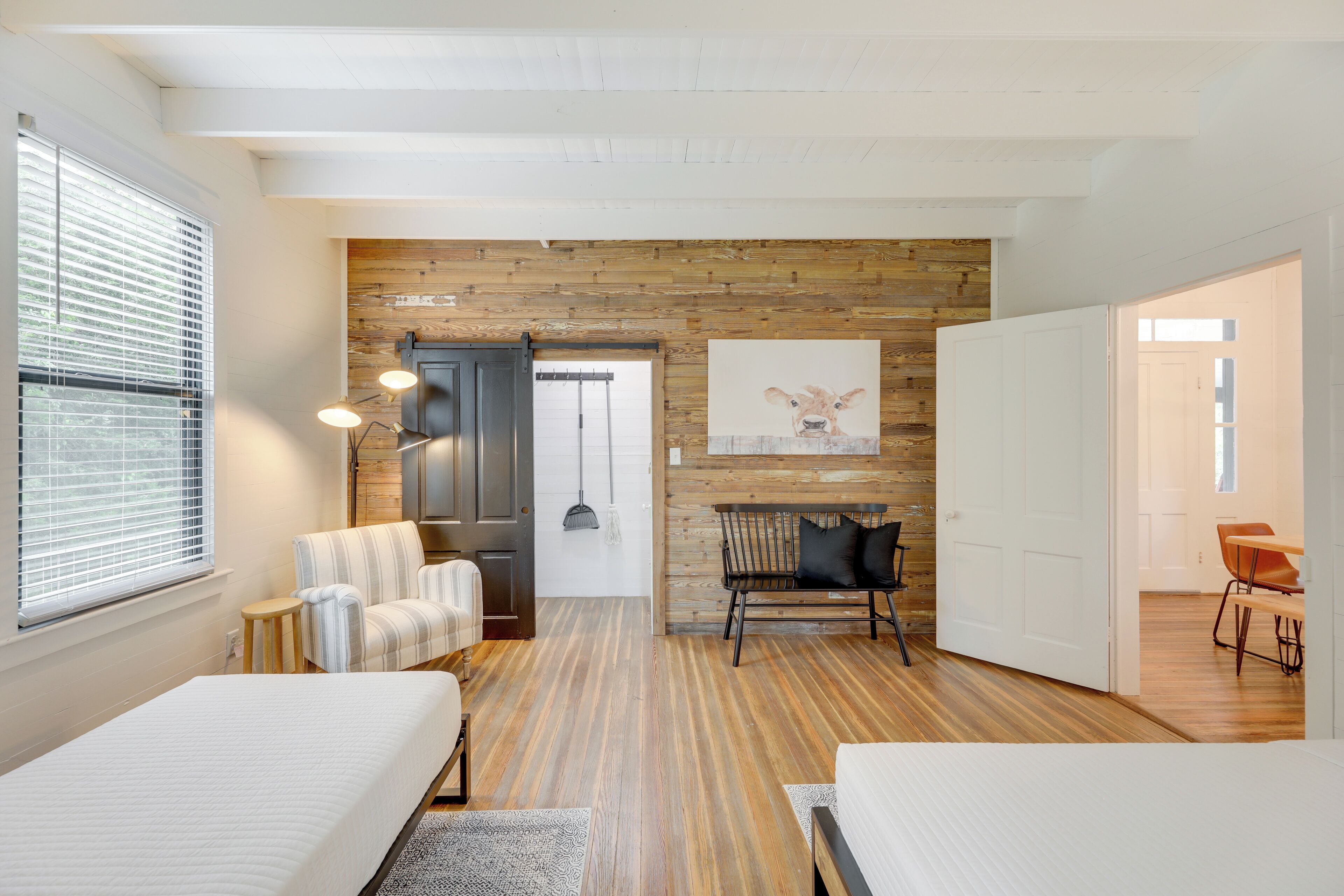 Een moderne hotelkamer met een houten accentmuur, een groot bed, een zithoek met een bank en stoelen, en een eettafel.