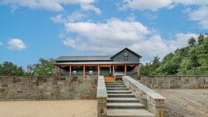 A stone-walled building with a covered porch and a staircase leading to a wooden deck. - Sip, Fish & Relax Fireside: Serene Schulenburg Gem (Schulenburg)