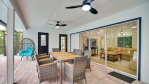 A patio area with a dining table and chairs, a ceiling fan, and a sliding glass door leading to a living room. - 'casa Blanco' Escape w/ Fire Pit in Sebastian! (Sebastian)