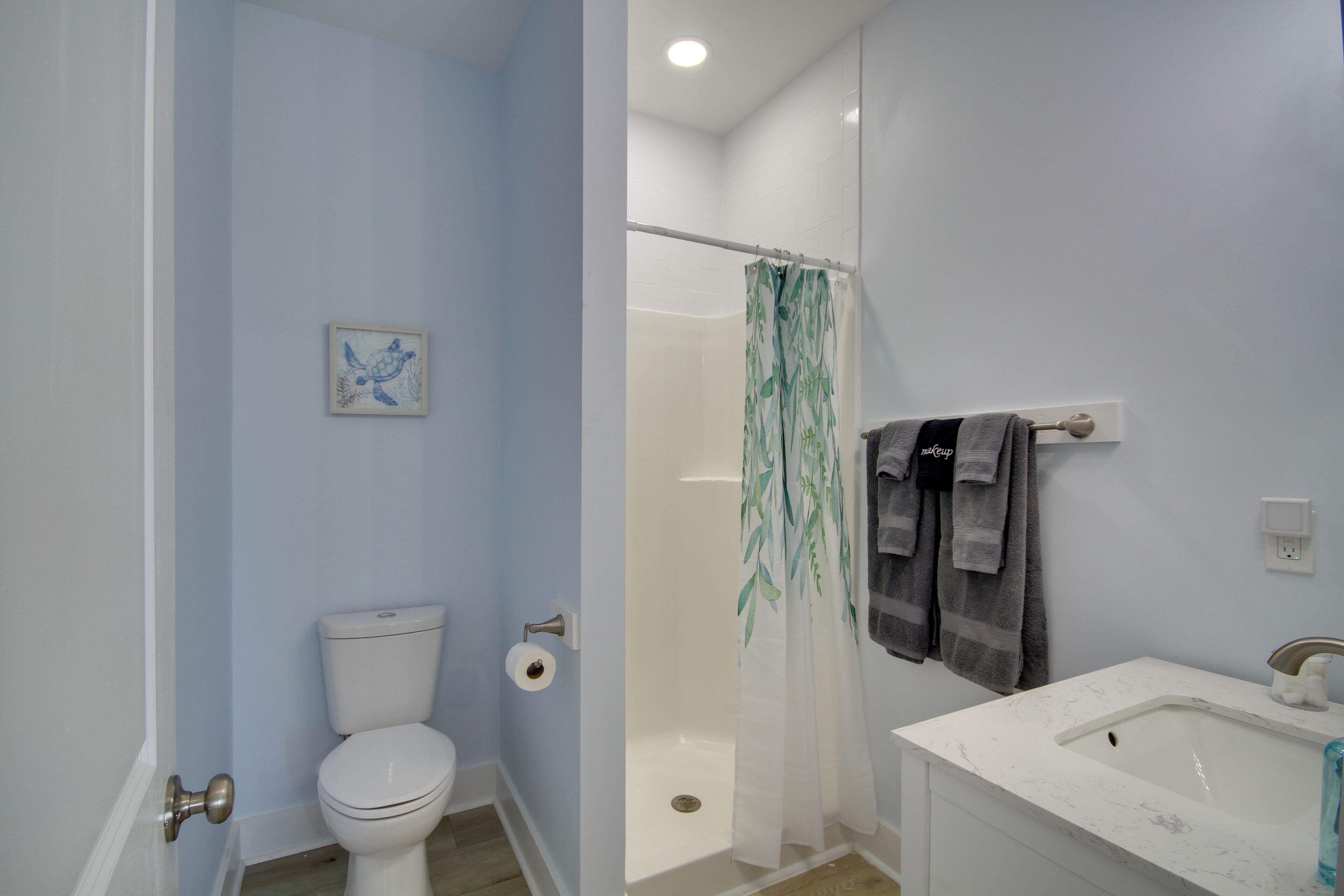 A bathroom with a toilet, shower, and sink.