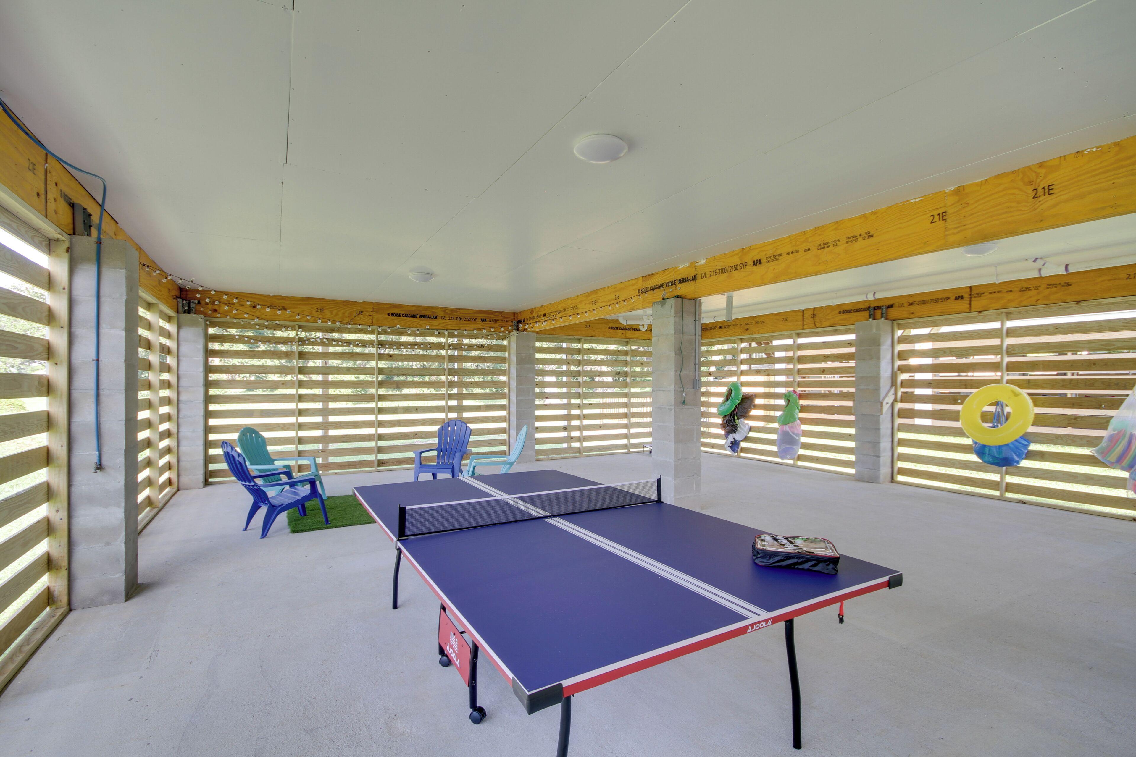 Ein Tischtennis-Tisch in einem Raum mit Holzbalken und einer Sprossenklimaanlage.