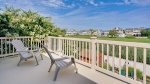 A balcony with two Adirondack chairs, a white railing, and a view of houses in the background. - Brigantine Vacation Rental w/ Private Pool! (Brigantine)