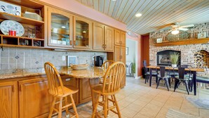 A kitchen with wooden cabinets, a granite countertop, and a dining area with chairs and a table. - Brigantine Vacation Rental w/ Private Pool! (Brigantine)