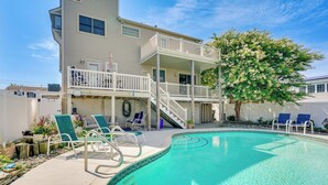 A two-story building with a balcony, a swimming pool, and lounge chairs. - Brigantine Vacation Rental w/ Private Pool! (Brigantine)