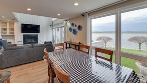 A modern living room with a dining table, sofa, and TV. - Luxury Lakefront Boyne City Townhome w/ Views! (Boyne City)