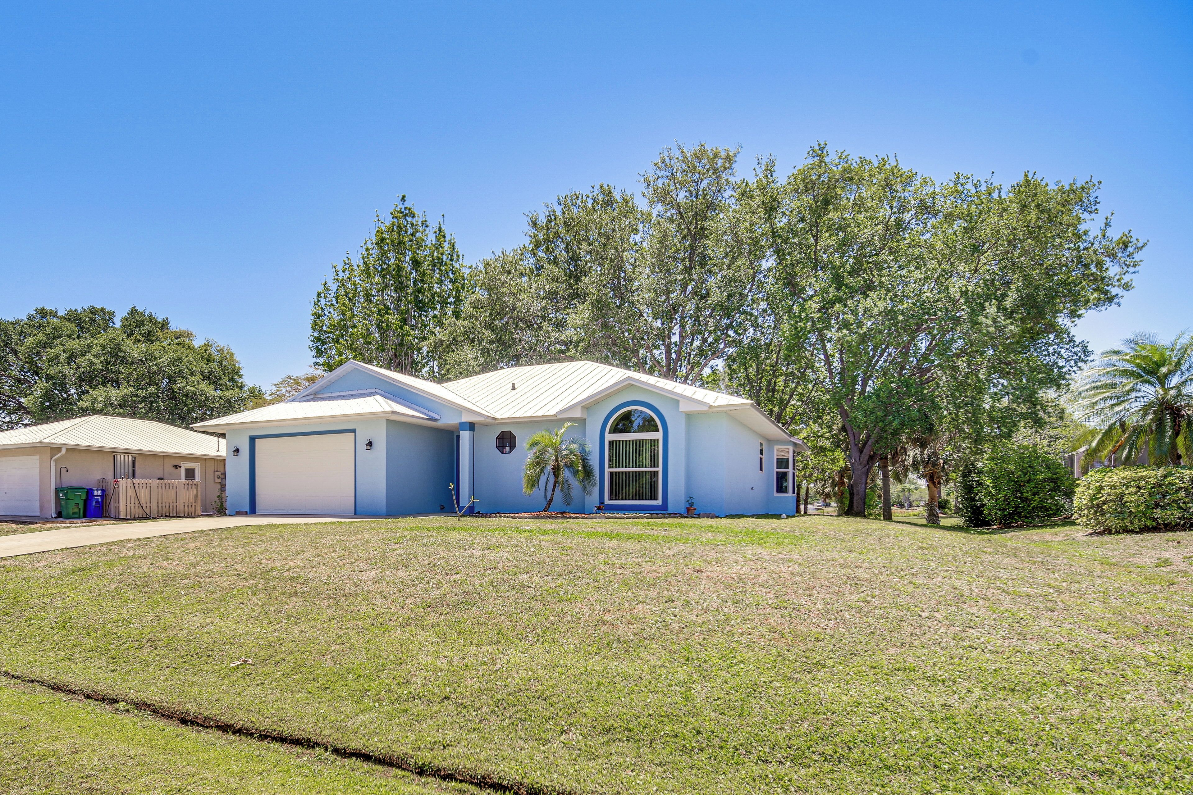 A single-story house with a blue exterior and a white garage door.