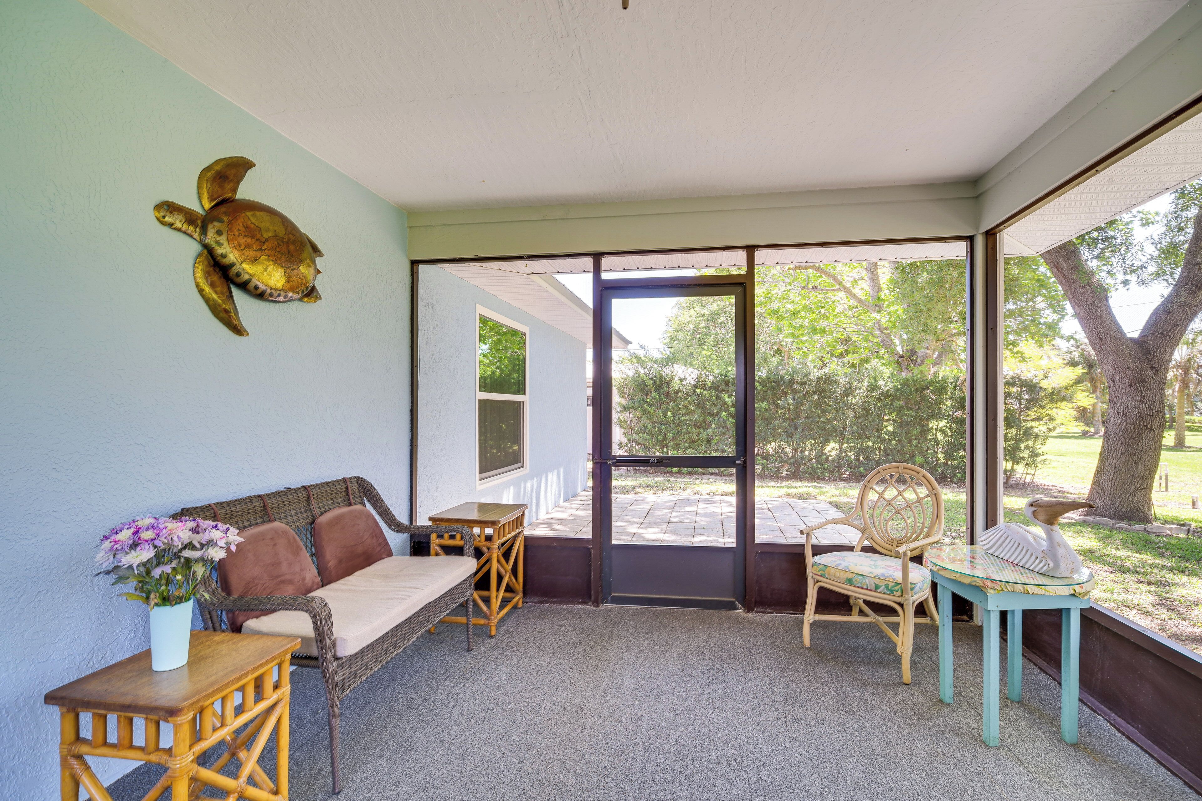 A room with a sofa, a small table with a vase of flowers, and two chairs.