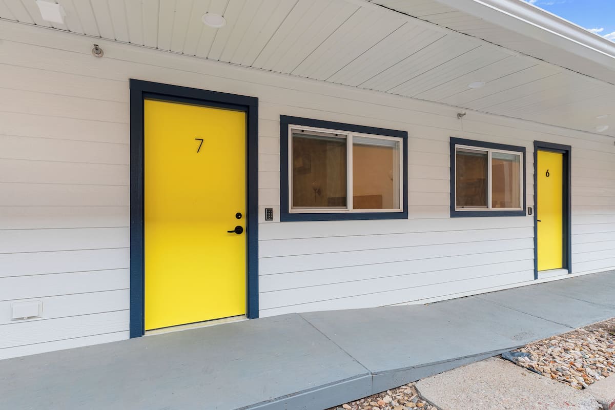 A row of white buildings with yellow doors numbered 7 and 6.