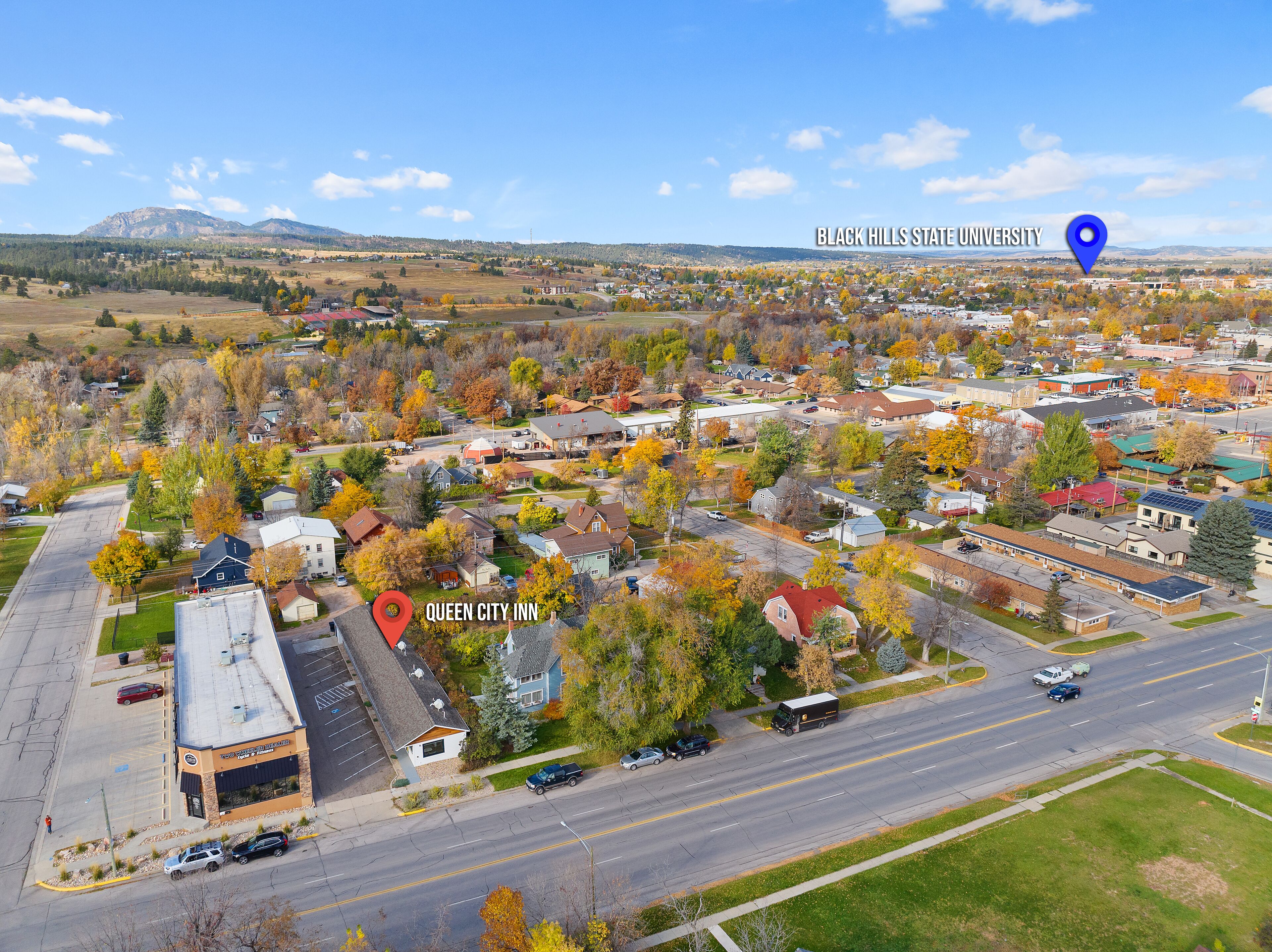 An aerial view of a town with a prominent building labeled "Queen City Inn."