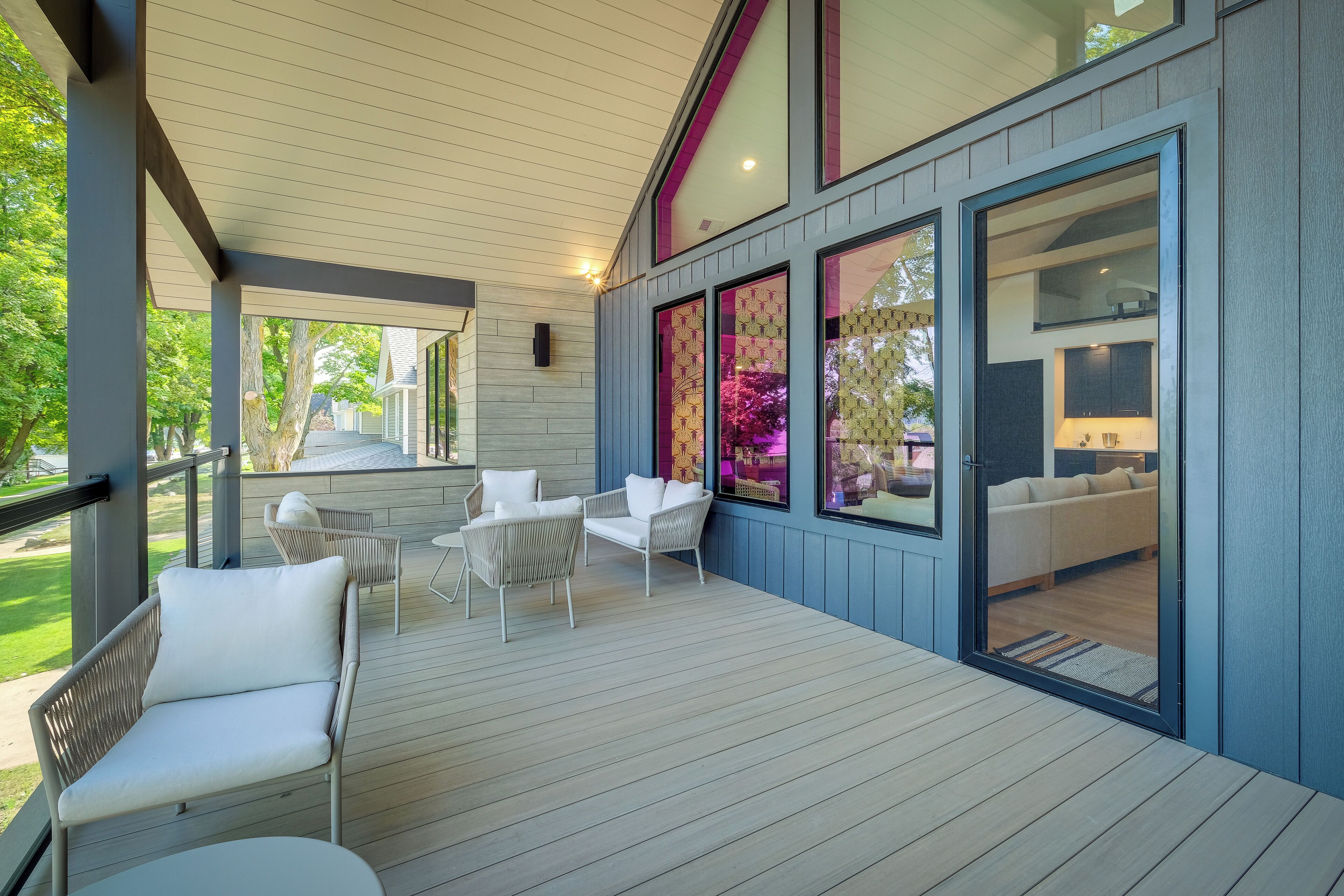 Een overdekt terras met witte rieten meubels en uitzicht op het huis.