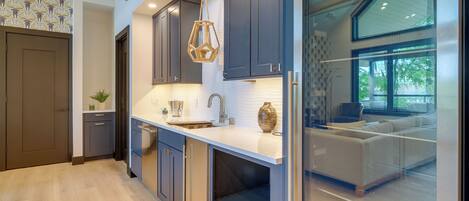 A modern kitchen with dark cabinets, a white countertop, and a hanging pendant light.