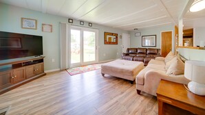 A spacious living room with a large flat-screen TV, a leather sofa, a beige couch, and a wooden coffee table. - Cozy Geneva Home: Walk to Lake Erie & Main Strip! (Geneva)