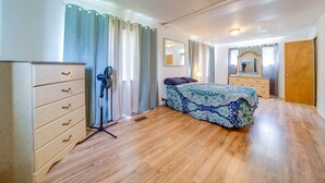 A bedroom with a bed, a dresser, a mirror, and a door. - Cozy Geneva Home: Walk to Lake Erie & Main Strip! (Geneva)