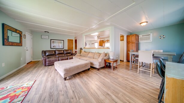 A spacious living room with a large sectional sofa, a small ottoman, and a dining area with a table and chairs. - Cozy Geneva Home: Walk to Lake Erie & Main Strip! (Geneva)