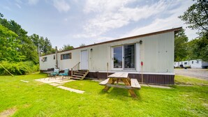 A mobile home with a patio area, a picnic table, and a small deck. - Cozy Geneva Home: Walk to Lake Erie & Main Strip! (Geneva)