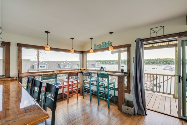 A wooden deck with a glass door leading to a balcony overlooking a marina. - Ocean-view Apt in the Heart of Southwest Harbor! (Southwest Harbor)
