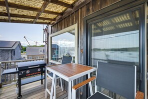 An outdoor patio with a grill, a table, and chairs. - Ocean-view Apt in the Heart of Southwest Harbor! (Southwest Harbor)