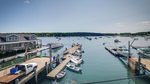 A marina with docked boats, a wooden pier, and a building with a dock. - Ocean-view Apt in the Heart of Southwest Harbor! (Southwest Harbor)
