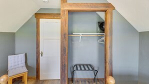Une pièce avec une porte en bois, une petite chaise en bois, une étagère en métal et un tabouret en bois.