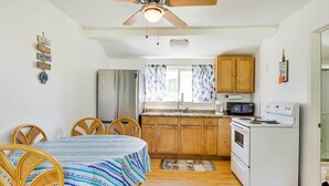 A compact kitchen with wooden cabinets, a microwave, a stove, and a dining area with a table and chairs. - Lakefront Geneva Vacation Rental - Walk to Strip! (Geneva)