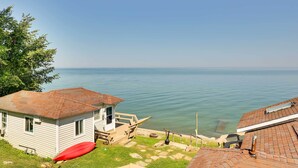 A small white cabin with a wooden deck and a red kayak, overlooking a calm lake. - Lakefront Geneva Vacation Rental - Walk to Strip! (Geneva)