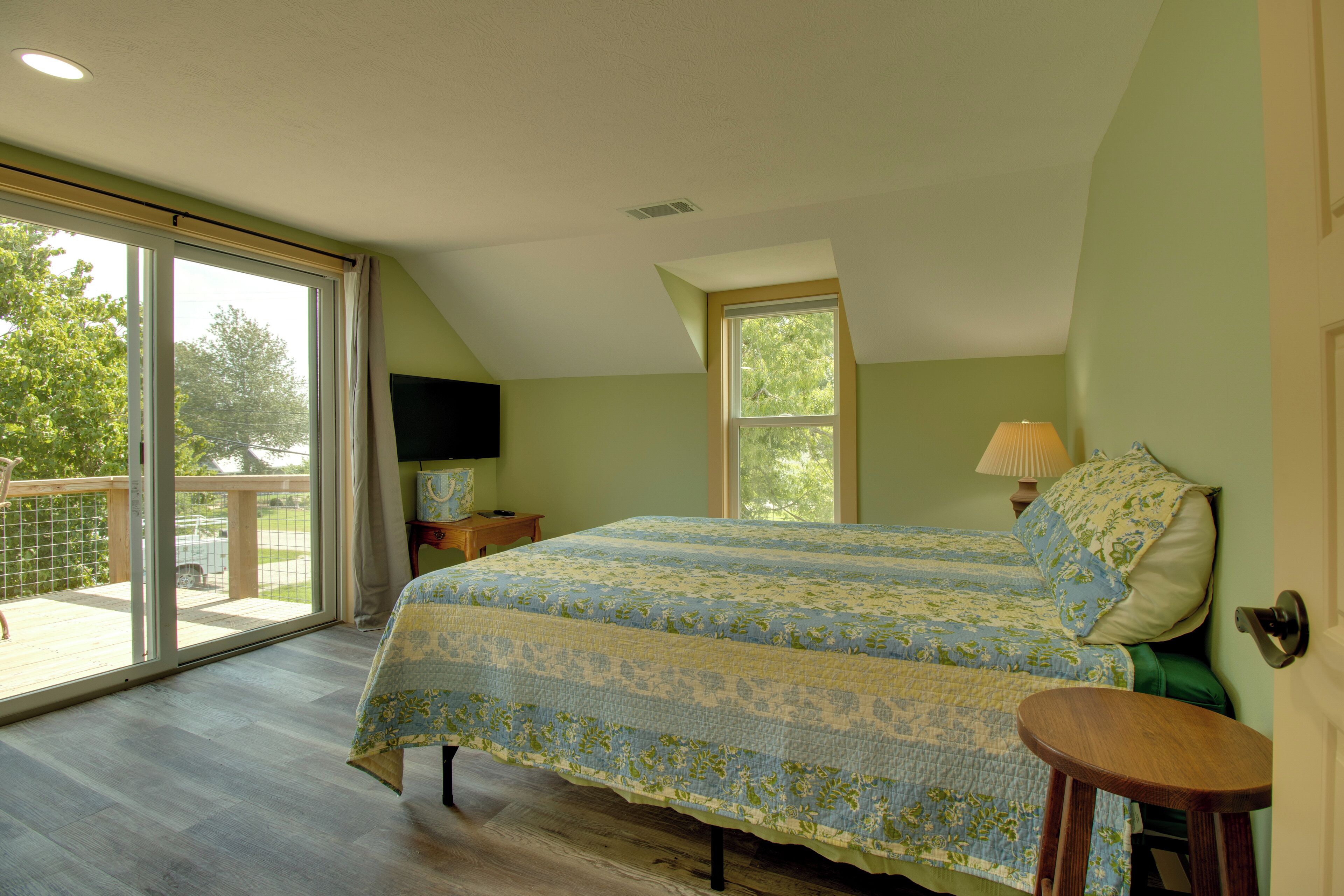 Un dormitorio con una cama grande, televisor, ventana y puerta.