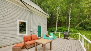 Eine Terrasse mit Gartenm öbeln, einem Grill und Blick auf den umliegenden Wald.