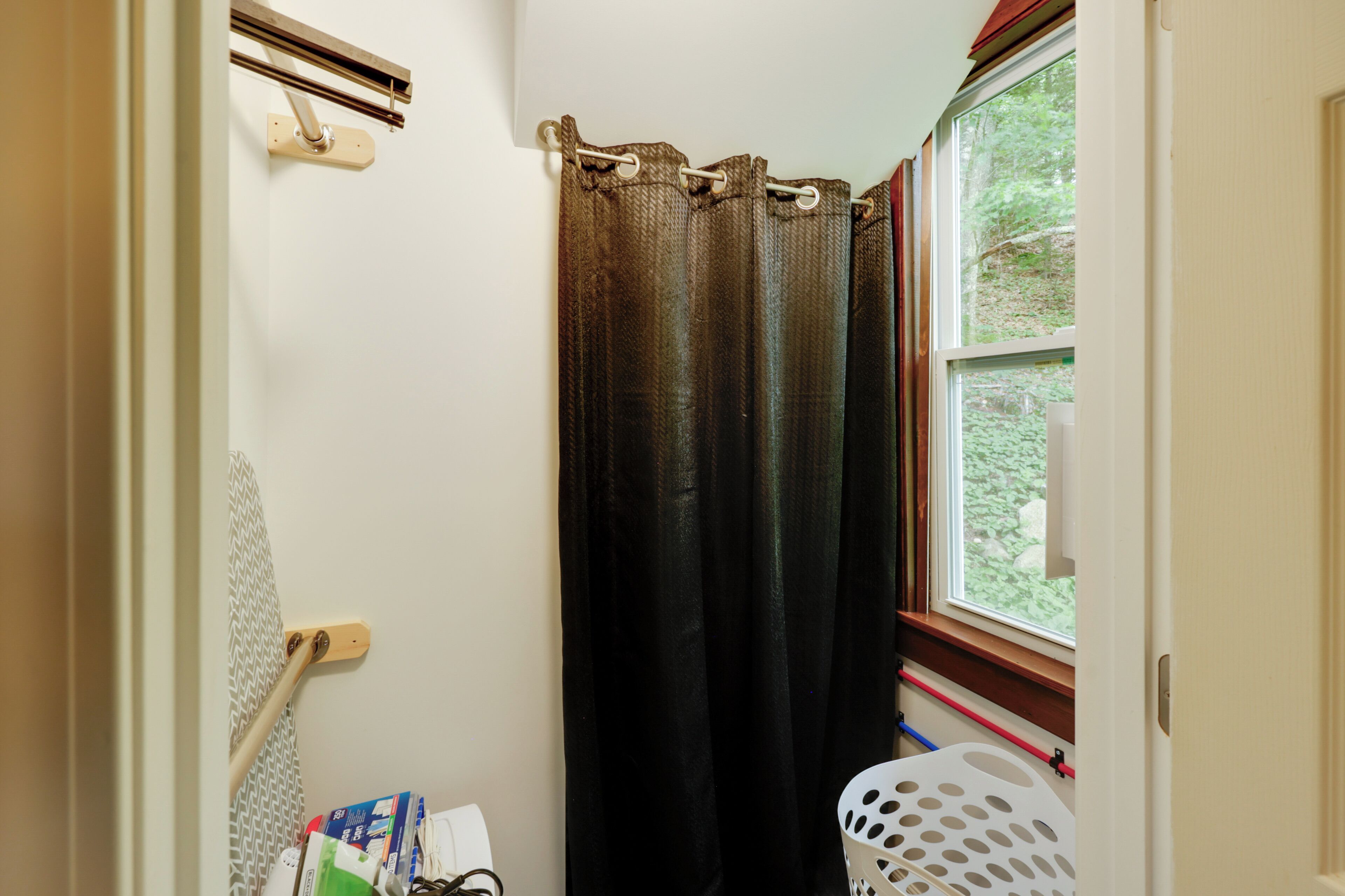 Une salle de bain avec un rideau de douche, une fenêtre et une porte.