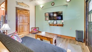 Une pièce confortable avec une porte en bois, un téléviseur fixé au mur, une petite table et un canapé.