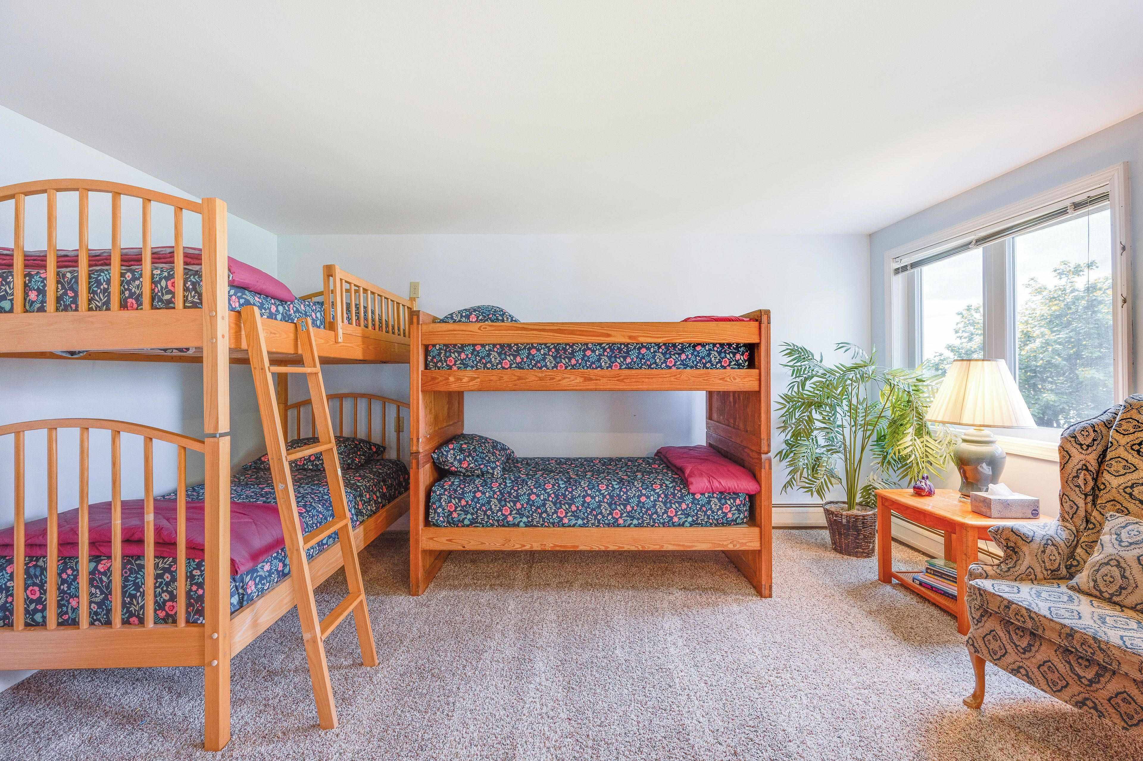 Quarto com beliche, sofá, luminária e janela.