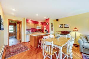 A spacious kitchen with wooden cabinets, a central island, and a dining area with white chairs.