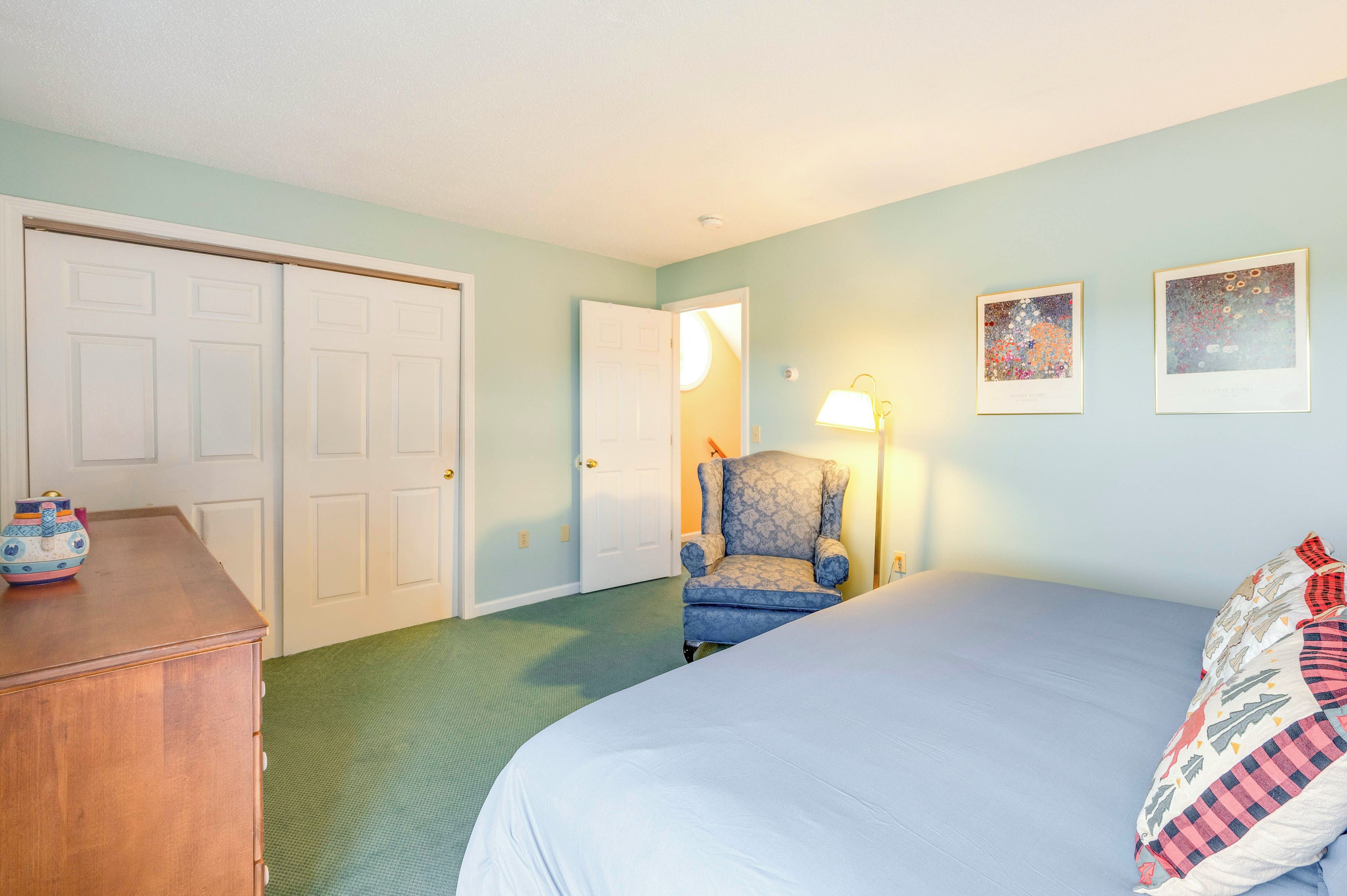 Une chambre à coucher avec un lit, une chaise, une commode et deux portes.