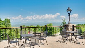 A patio with a stone fireplace, metal chairs, and a table.