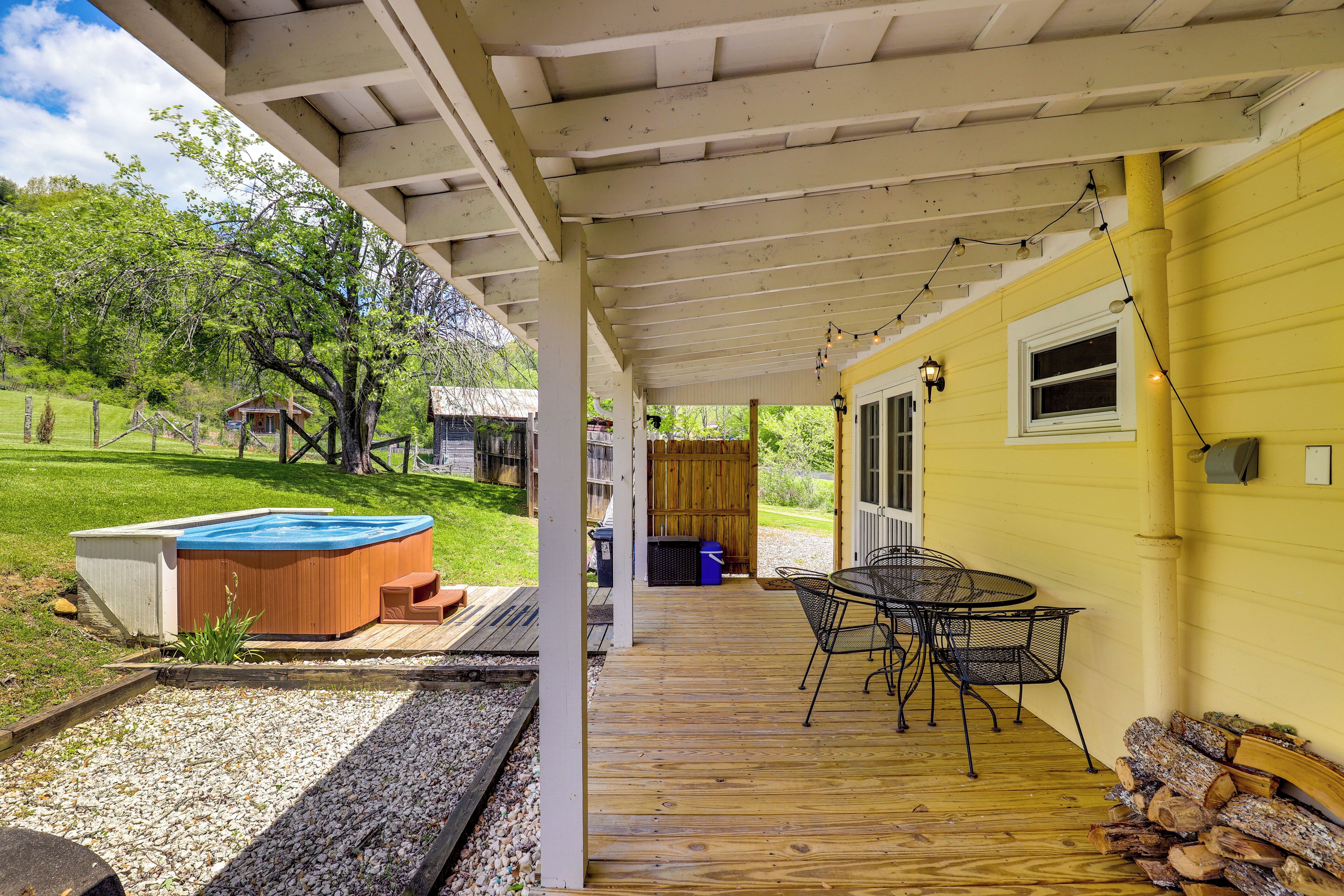 Eine überdachte Terrasse mit Whirlpool, Holzdeck und Sitzgelegenheit im Freien.