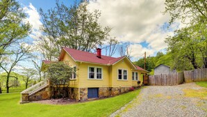 A yellow house with a red roof, a stone staircase, and a wooden fence.