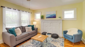 A living room with a sofa, armchair, coffee table, and a fireplace.