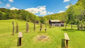A grassy field with picnic tables and a rustic barn.