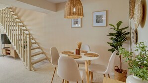 Ein Essbereich mit einem runden Tisch, vier Stühlen, einer Treppe und einer Hängelampe.