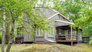 Eine Holzhütte mit Veranda, umgeben von Bäumen und einem Rasenstück.