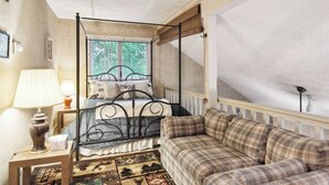 Ein Schlafzimmer mit einem Himmelbett, einer karierten Couch, einer Lampe und einem Teppich.