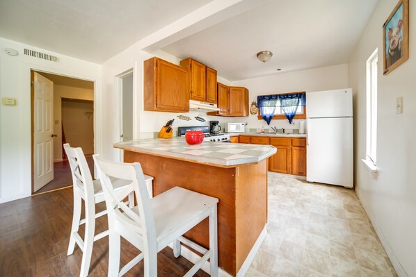 A kitchen with wooden cabinets, a white refrigerator, a coffee maker, and a red kettle on the counter.