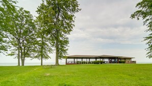 A covered pavilion with a view of the ocean, surrounded by grass and trees. - Charming Lake Erie Cottage on Main Strip! (Geneva)