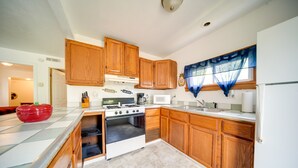 A kitchen with wooden cabinets, a stove, and a microwave. - Charming Lake Erie Cottage on Main Strip! (Geneva)